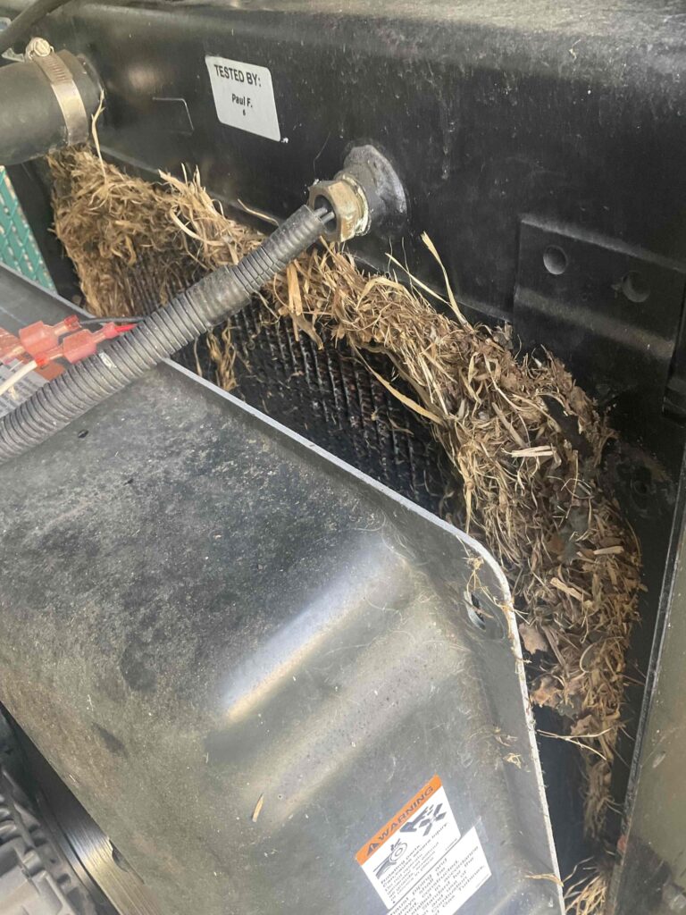 A generator cooling system filled with debris such as leaves, grass, branches. The debris is obstructing airflow to the generator’s radiator, increasing the risk of overheating.