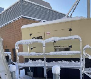 Why Your Generator Needs a Block Heater | A generator covered in snow and ice after a recent storm, but the generator's block heater is keeping the coolant and engine block warm for enhanced reliability.