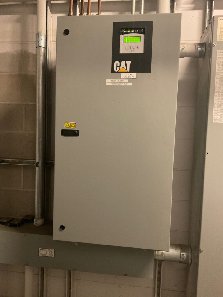 A close-up image of a CAT transfer switch. The transfer switch is installed on a wall with visible labels for various components, ensuring proper power transfer during an outage for a nursing home in Hartford Connecticut.