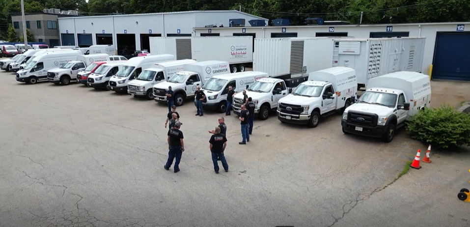 Weld Power Generator technicians at a safety meeting. In the background there is the fleet of generator service vehicles, trailer mounted generator rentals, and Weld Power Generator's headquarters.