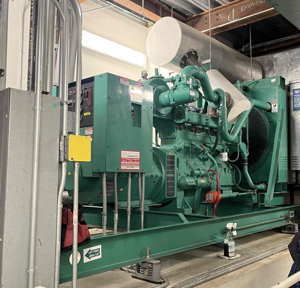 A complete Cummins generator unit showcasing the radiator, exhaust system, generator engine, and generator head (alternator). The generator is providing back up power to a hospital in New Jersey.