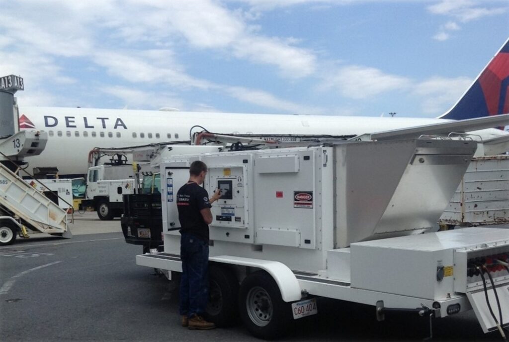 Weld Power generator Technician completing a load bank test on a generator at Logan Airport with a Delta Plane in the background.