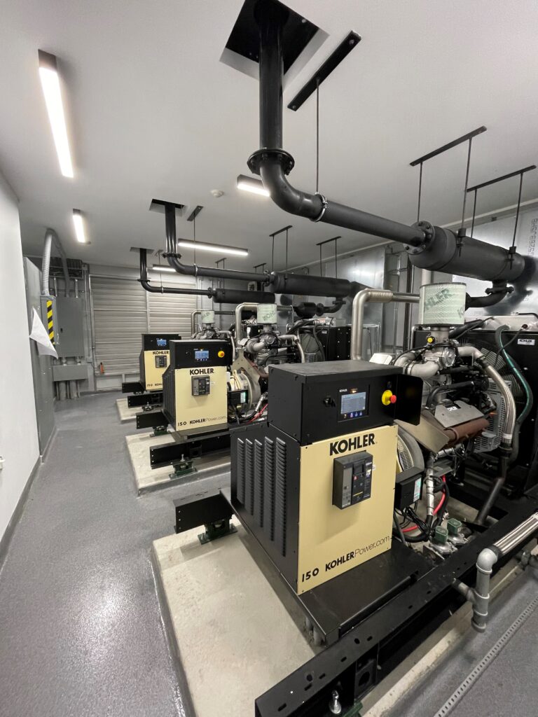Three Kohler generator units that are extremely clean and well maintained. The photo showcases the generator engine, generator head, and the exhaust system. The generators are inside a nursing home in Connecticut.