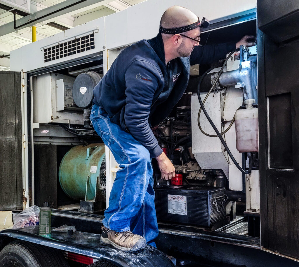 Weld Power Generator service technician performing maintenance on a portable generator.