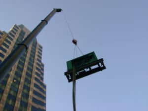 HiPower Generator Installation on the rooftop of a building in New York City. Generator is being suspended in the air by a crane. 