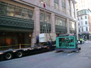 HiPower Generator Installation on the rooftop of a building in New York City. Generator is being suspended in the air by a crane. 
