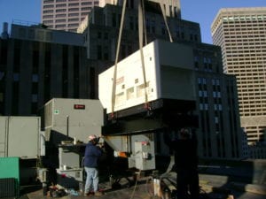HiPower Generator Installation on the rooftop of a building in New York City. Generator is being suspended in the air by a crane. 